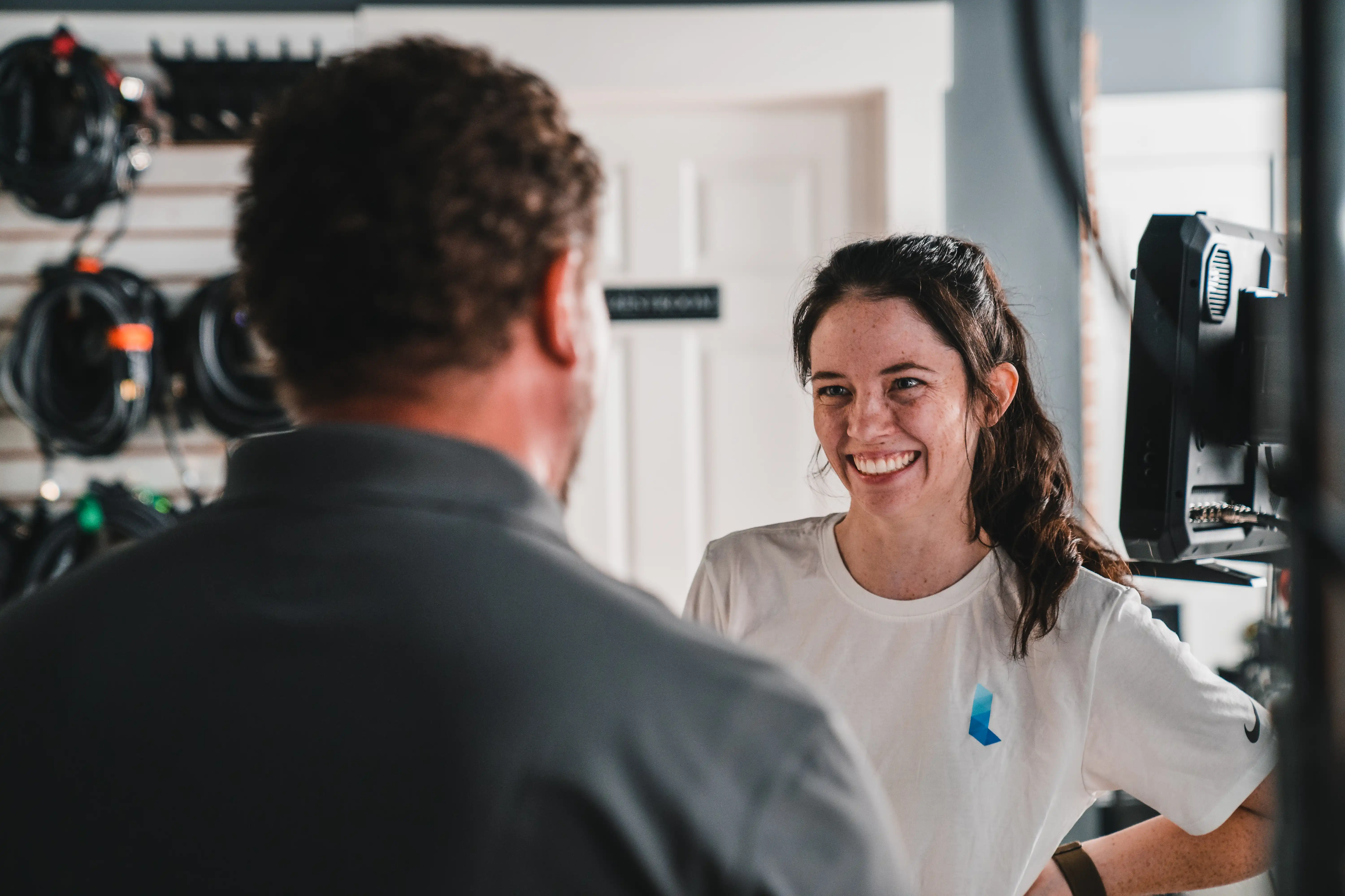 A producer smiling and interacting with a director. The producer and director are engaged in a positive conversation on set.